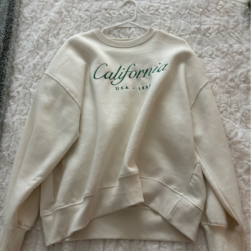 Beige California crewneck with green stitching for the letters